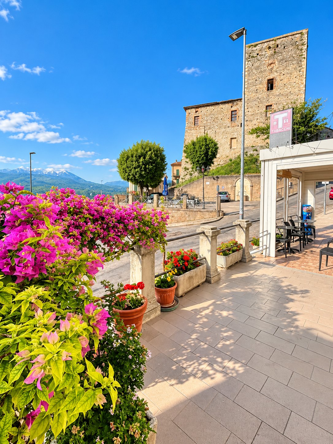 La piazza di Rosciano vista dall'ingresso di TorreViva, con i fiori, la torre medievale e l'insegna del tabacchi