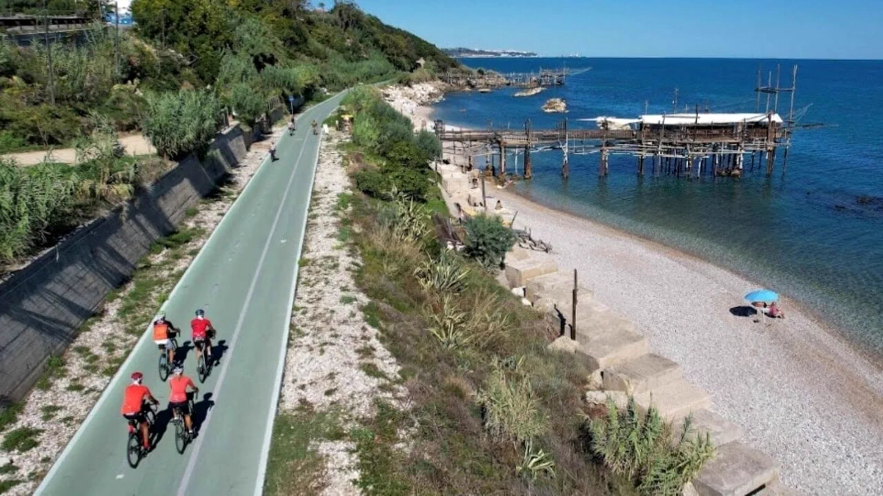 Ciclisti sulla Via Verde accanto alla spiaggia e a un trabocco
