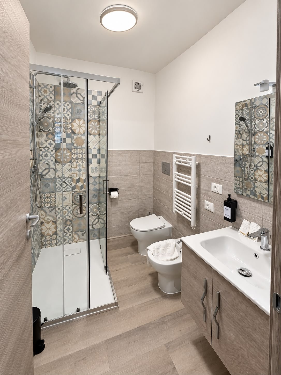 Bagno privato completo con doccia, piastrelle decorative e set di cortesia